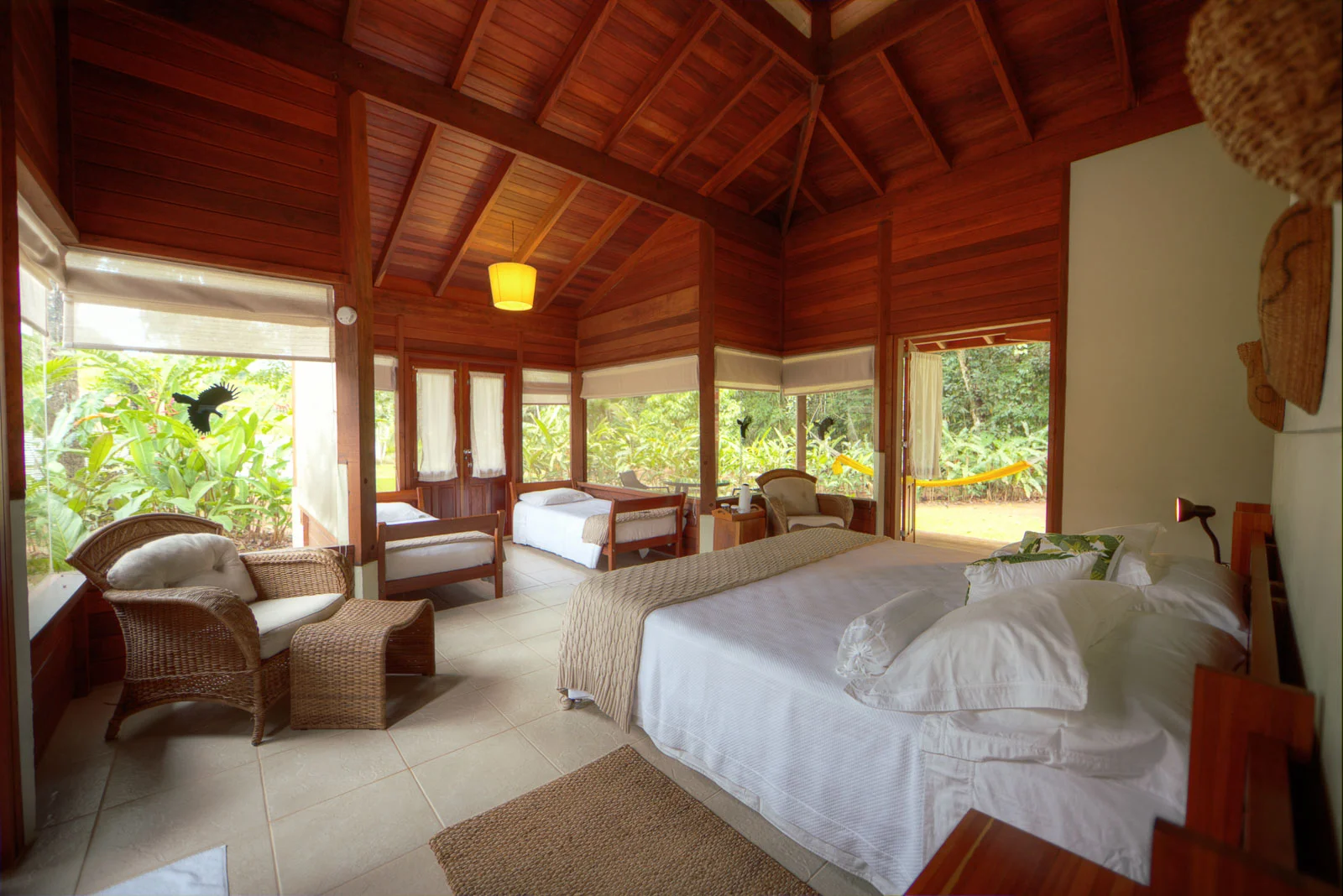 interior shot of a bungalow at Cristalino Lodge, showing a king size bed and two twin day beds